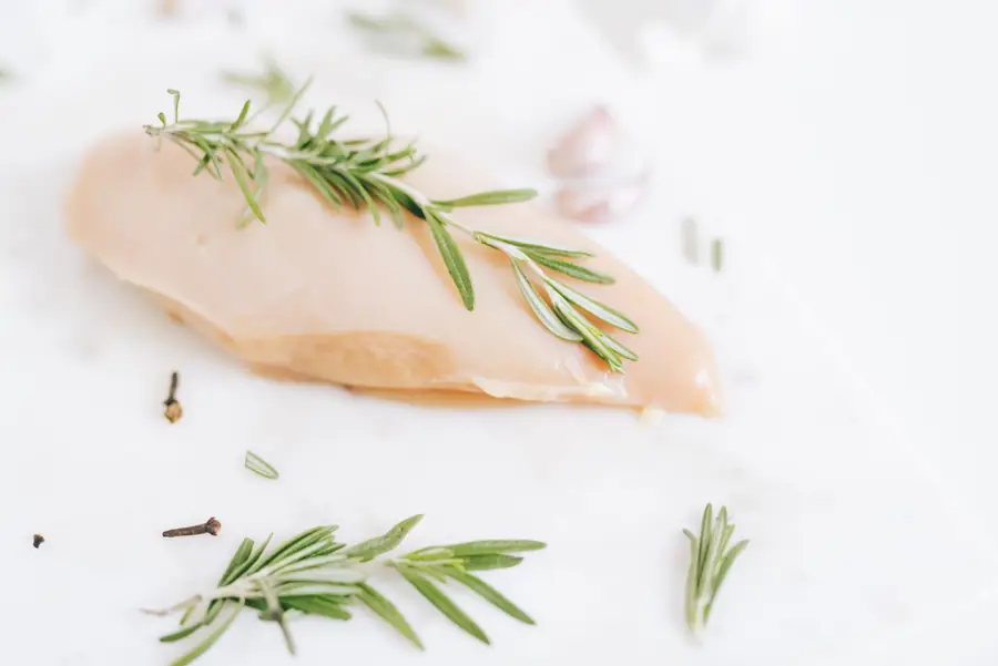 Raw chicken breast with a sprig of rosemary